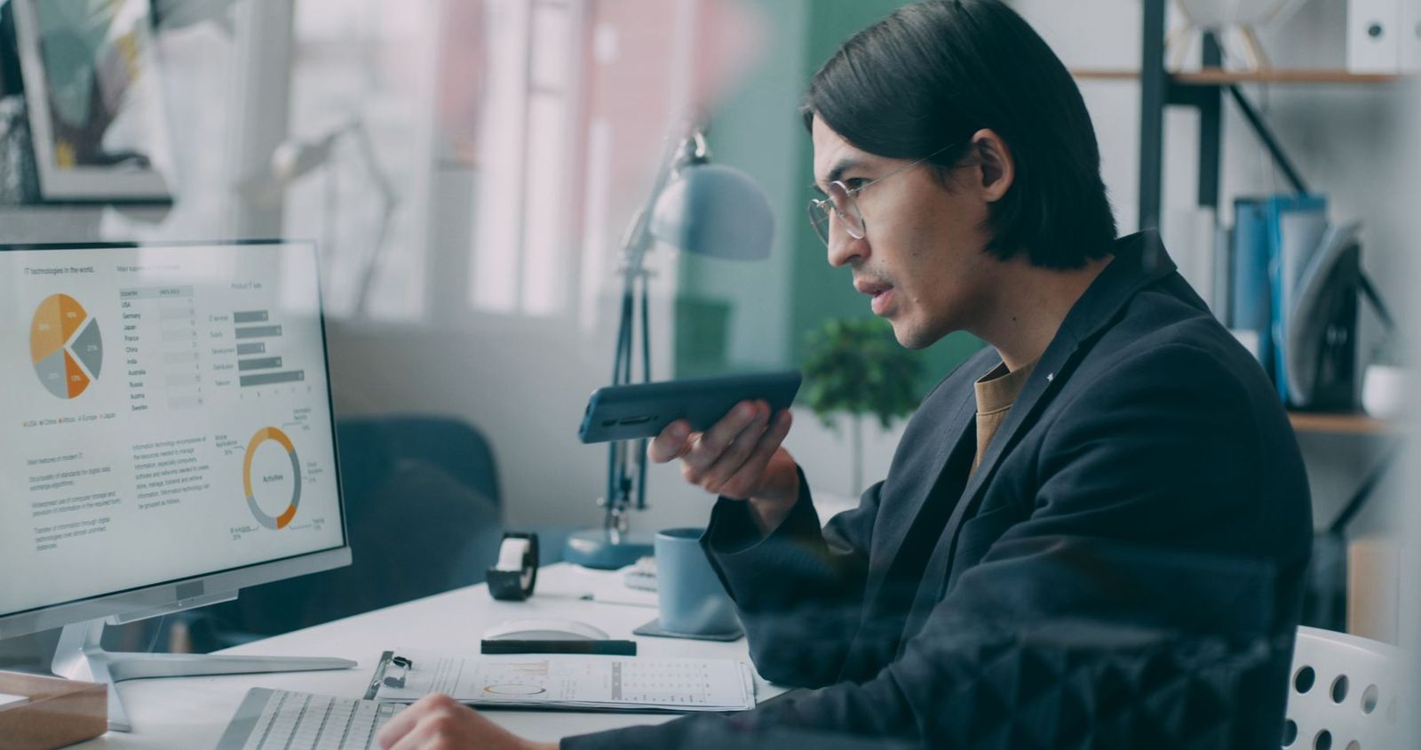 Business professional reviewing data charts on a computer screen while on a phone call