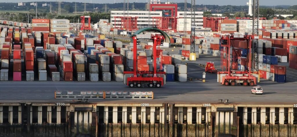 Container terminal with stacked shipping containers and straddle carriers at a port