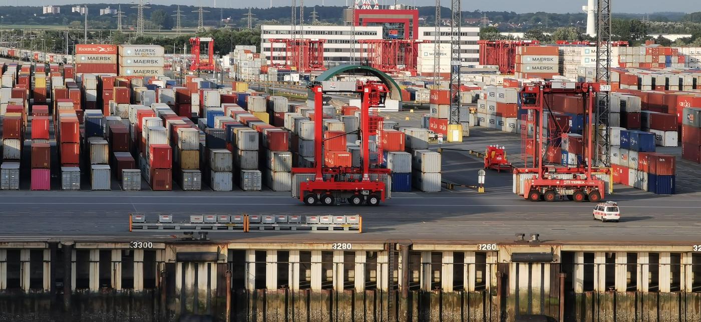 Aerial view of shipping containers and red gantry cranes at a container terminal
