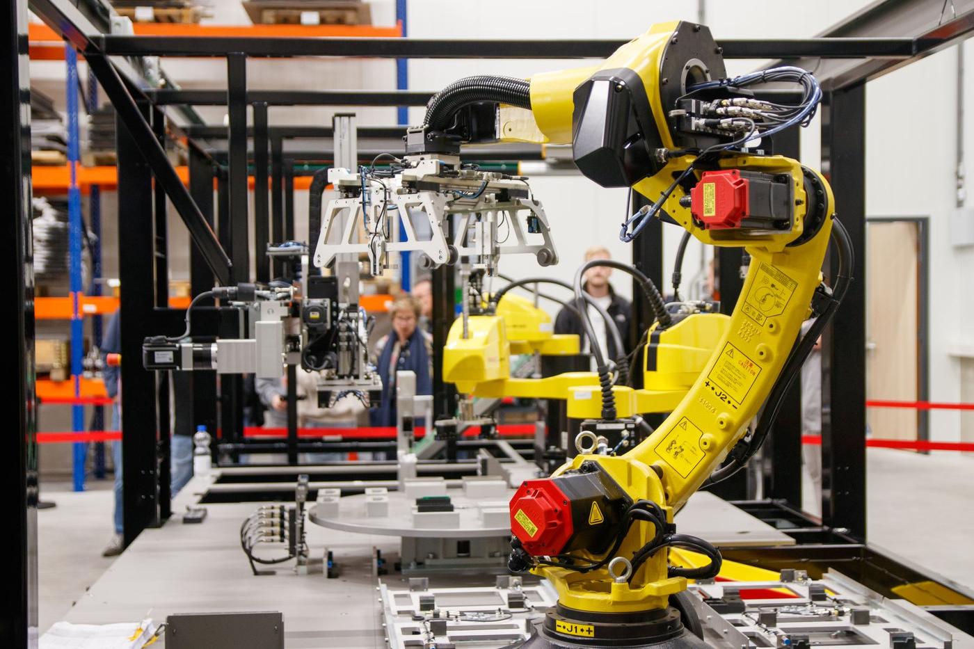Yellow industrial robotic arm working inside a bright, modern manufacturing facility
