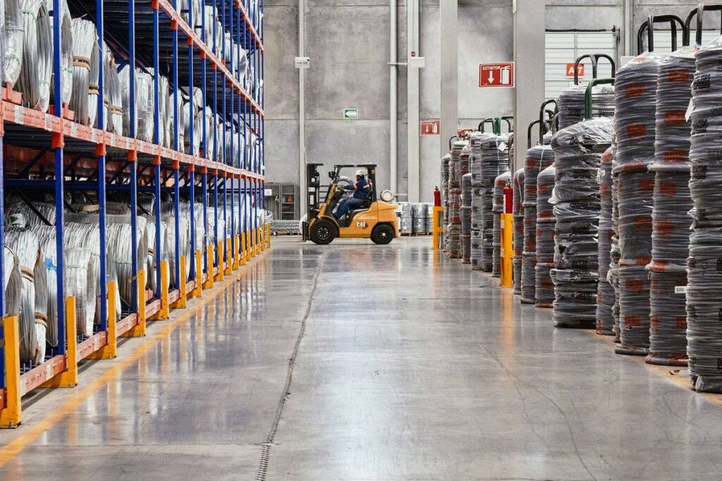 Warehouse aisle with high racking of wire coils and a forklift in the background